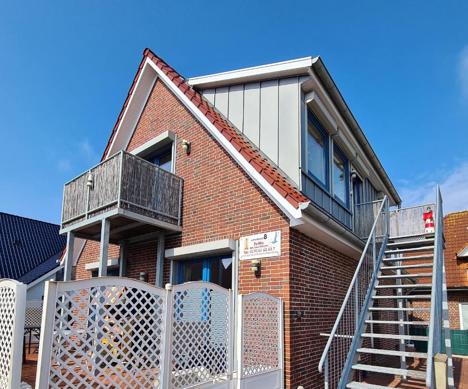 a brick house with a staircase and a balcony at Ferienwohnung Leuchtturm am Sandstrand in Norden