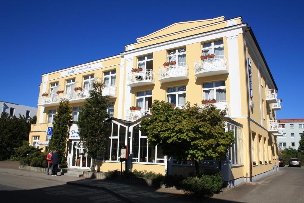 a yellow building with white balconies on a street at Hotel Poseidon in Kühlungsborn