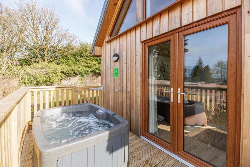 una vasca idromassaggio sul terrazzo di una casa di Kestrel Lodge 3 with Hot Tub a Newton Stewart