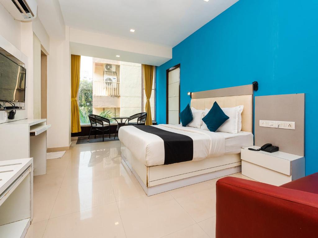 a bedroom with a large bed and a blue wall at Hotel Aura - Near Malad Link Road in Mumbai
