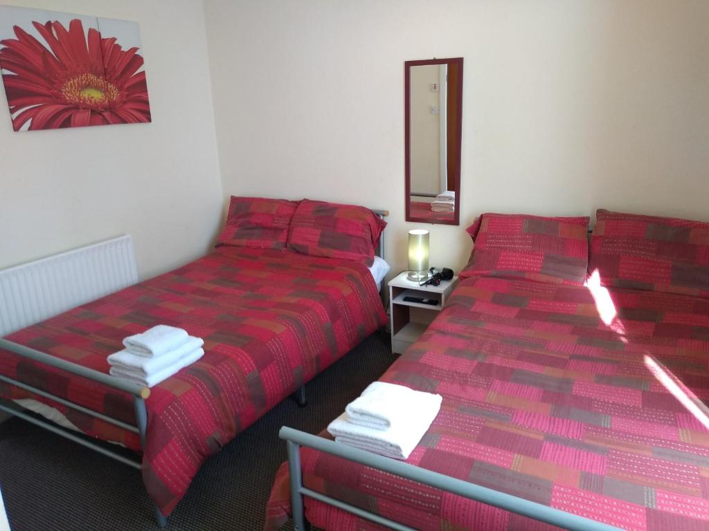 two beds in a room with red sheets and a mirror at Southview Hotel in Blackpool