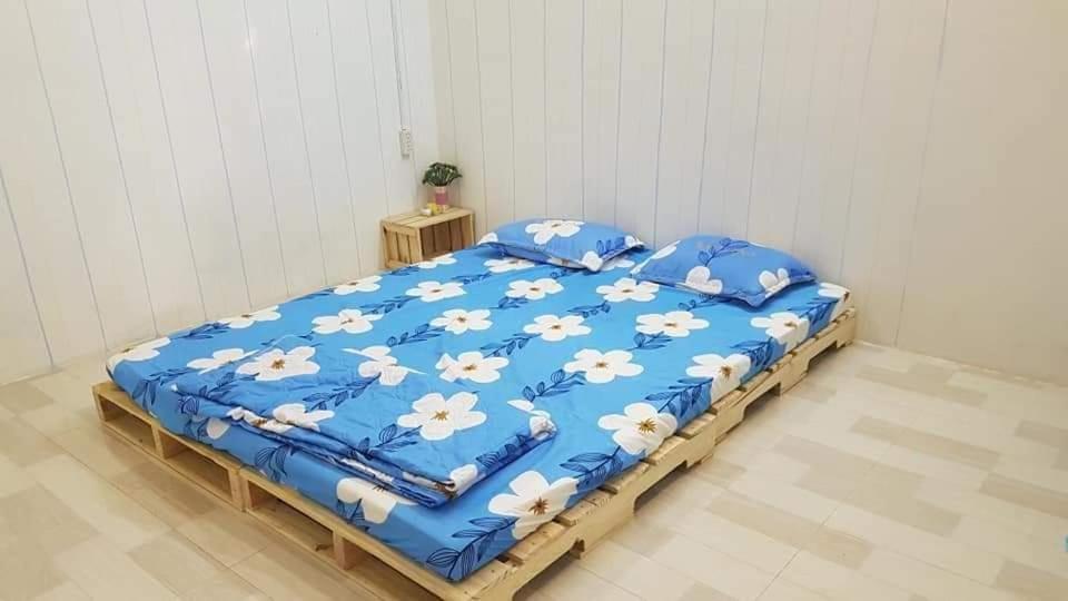 ein Bett mit blauer Bettwäsche und weißen Blumen darauf in der Unterkunft Homestay HP Rạch Giá in Rạch Giá