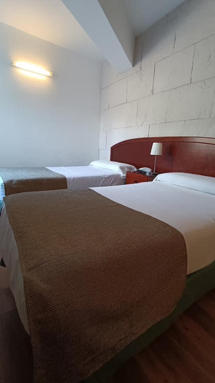 a hotel room with two beds and a lamp at Hotel Boomerang in Valverde