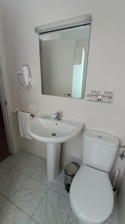 a white bathroom with a toilet and a sink at Hotel Boomerang in Valverde