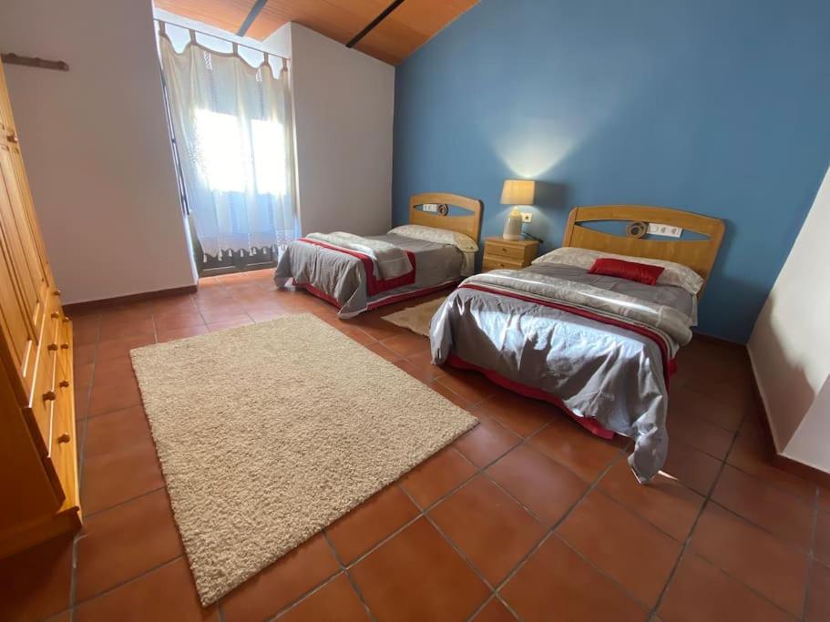 2 łóżka w pokoju z niebieskimi ścianami i podłogą wyłożoną kafelkami w obiekcie Casa Rosalía w mieście Encinasola