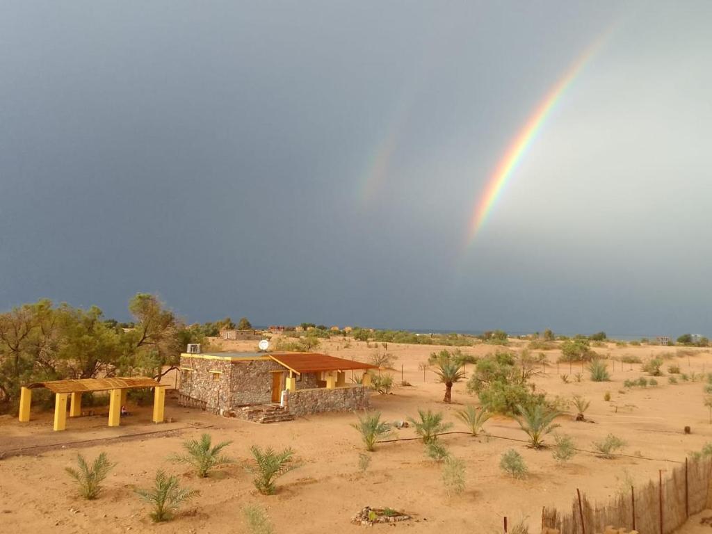 a rainbow in the middle of a desert with a building at Bayt Noon in Wāsiţ