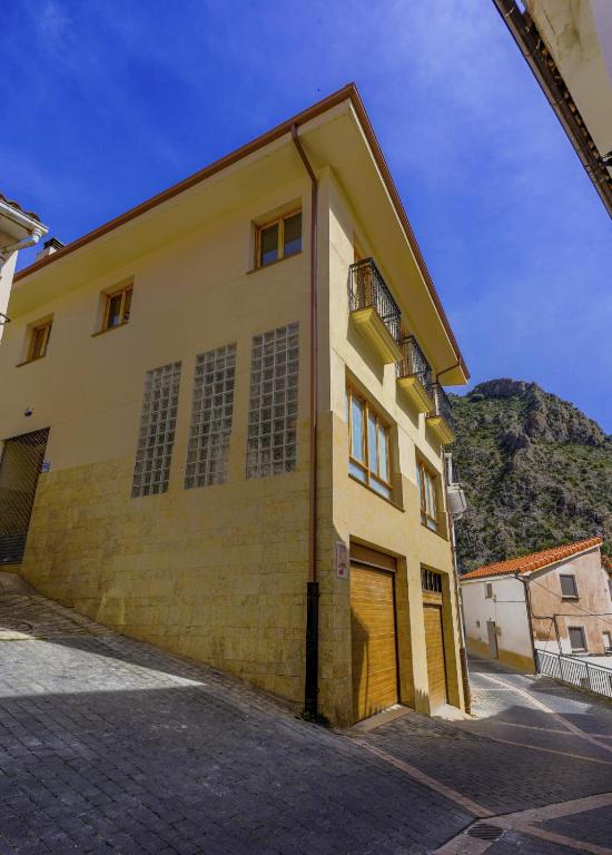 duży żółty budynek z górą w tle w obiekcie Barranco de la Olla by Apartamentos Arnedillo w mieście Arnedillo