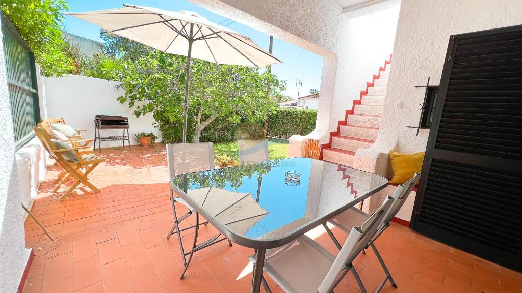a glass table and chairs with an umbrella on a patio at Villa Cabanas de Tavira by Sunny Deluxe in Tavira