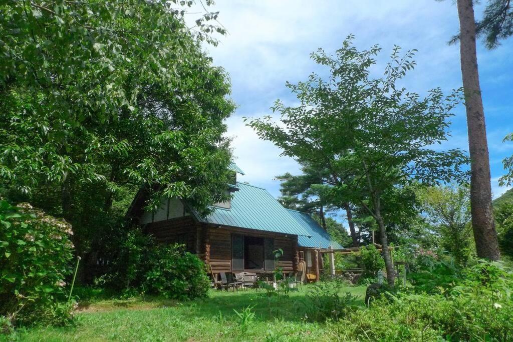 a log cabin with a green roof and trees at kaso Space kamiyama Log House 
