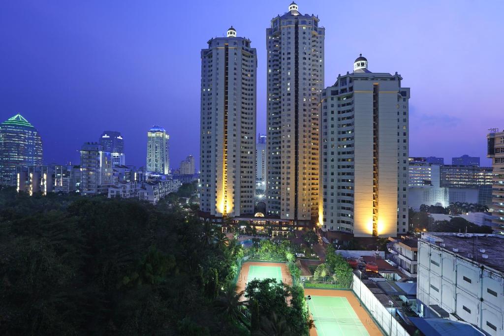 Aryaduta Suite Semanggi في جاكرتا: أفق المدينة في الليل مع المباني الطويلة