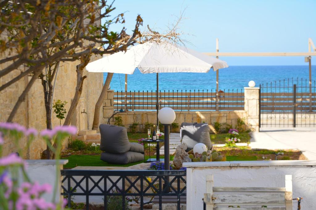 um pátio com cadeiras e um guarda-sol e o oceano em MariMar em Balíon