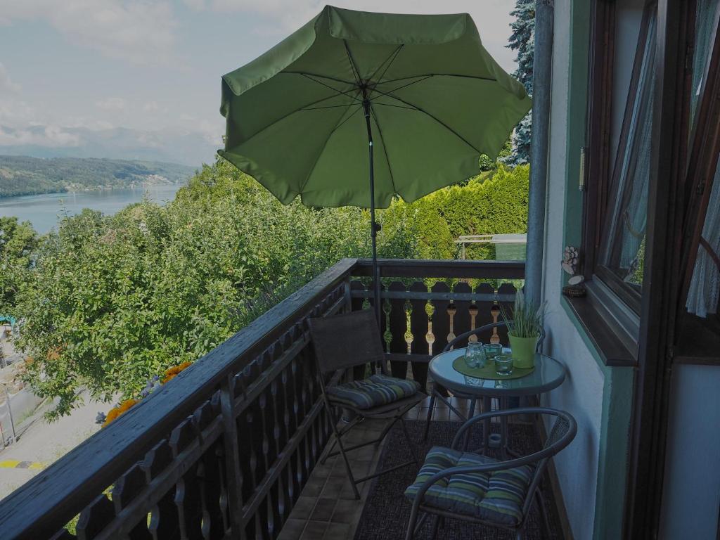 einen Tisch und Stühle mit Sonnenschirm auf dem Balkon in der Unterkunft Haus Herberg Millstatt in Millstatt