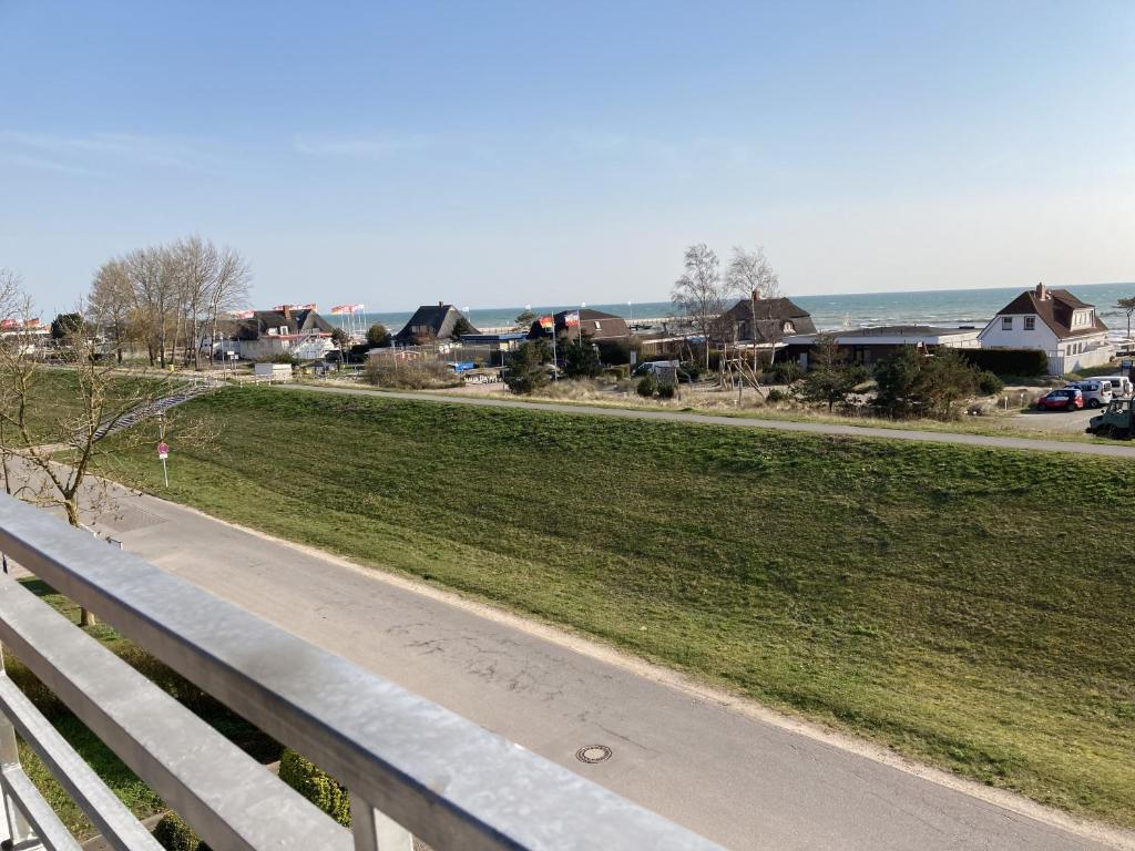 uma estrada ao lado de um campo com casas e o oceano em Haus am Deich Wohnung 13 em Dahme