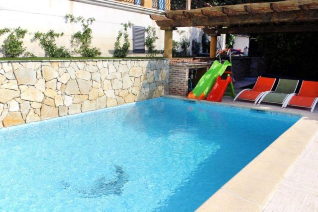 a swimming pool with a slide and a playground at COSY COTTAGE with private pool in La Turbie