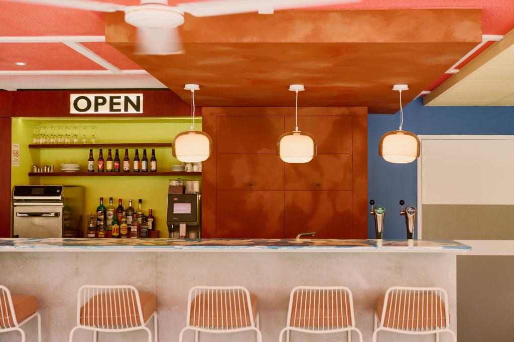 - un bar avec des chaises et un comptoir avec des bouteilles dans l'établissement Greet Hotel Versailles - Voisins Le Bretonneux, à Voisins-le-Bretonneux