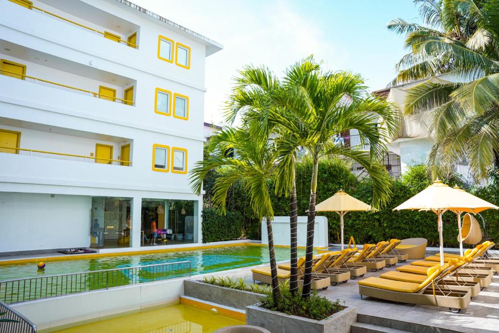 a hotel with a pool and lounge chairs and palm trees at Bloom Hotel - Calangute in Calangute