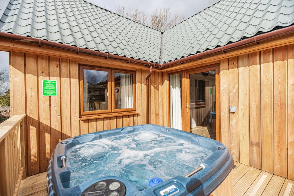 a hot tub sitting on the deck of a wooden house at Osprey Lodge 1 with Hot Tub in Newton Stewart