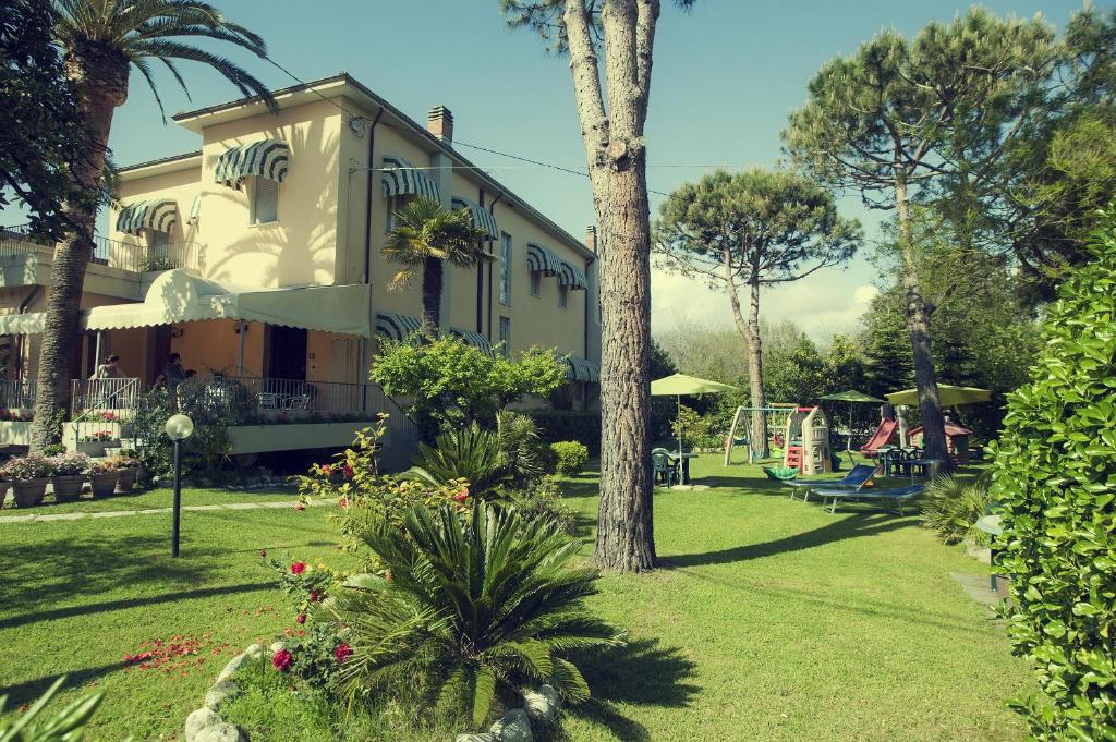 ein Haus mit einem Hof mit einem Spielplatz und einem Baum in der Unterkunft Hotel Parma Mare in Marina di Massa