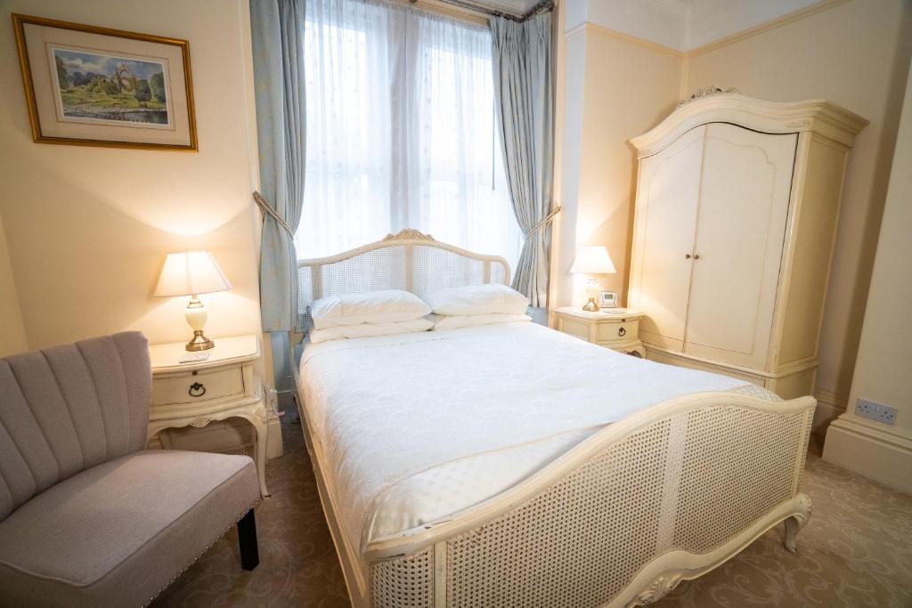 a bedroom with a white bed with a window and a chair at Barbican House in York