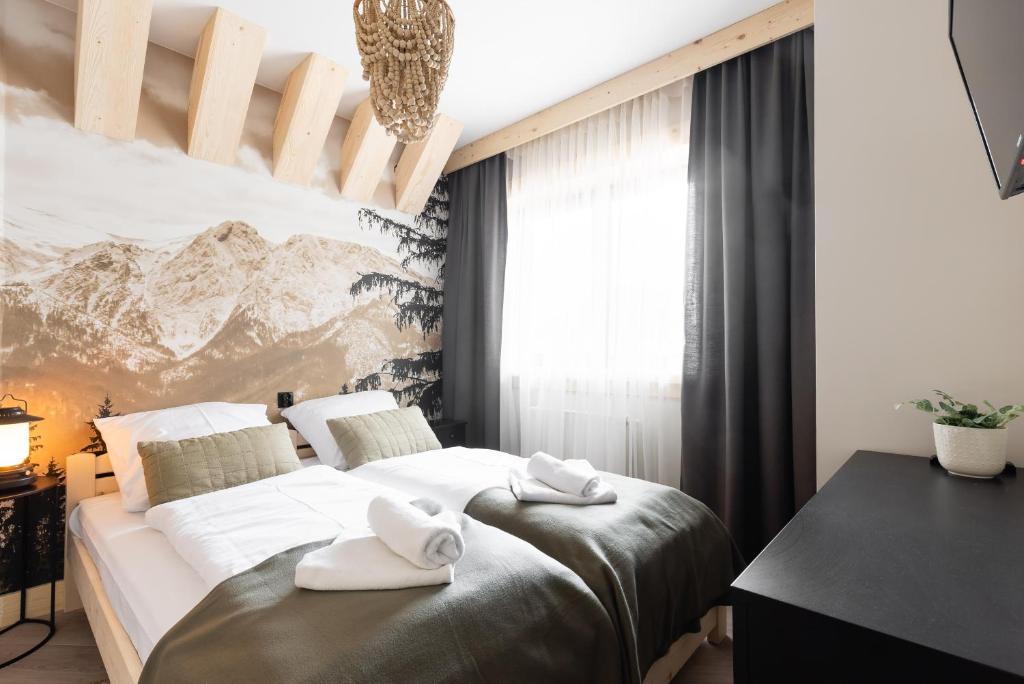 sypialnia z łóżkiem z białymi ręcznikami w obiekcie Apartamenty Smrekowa Tatry Zakopane w Zakopanem