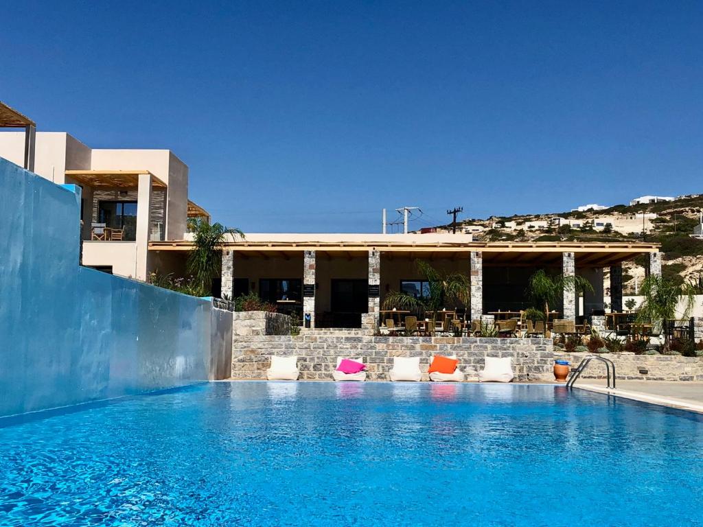 a swimming pool with chairs in front of a building at Helios Beach Hotel & Bungalows in Karpathos Town