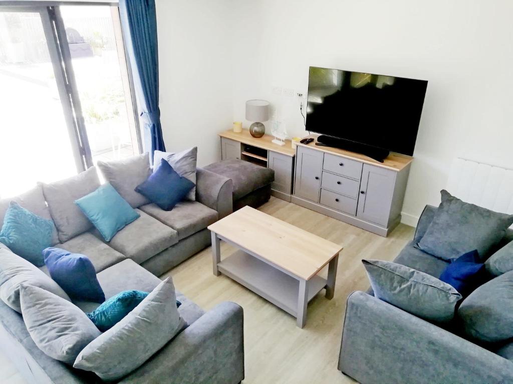 Una sala de estar con dos sofás y un televisor. en 2 Challacombe - Luxury Apartment at Byron Woolacombe, only 4 minute walk to Woolacombe Beach!, en Woolacombe