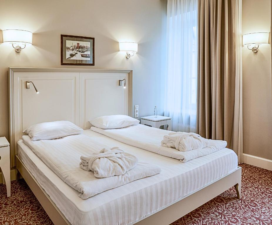 a bedroom with a large white bed with towels on it at Ratonda Centrum Hotels in Vilnius