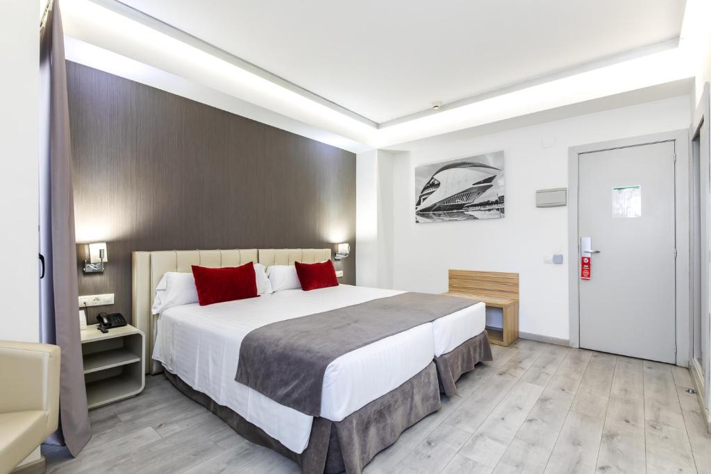 a bedroom with a large bed with red pillows at Sweet Hotel Renasa in Valencia