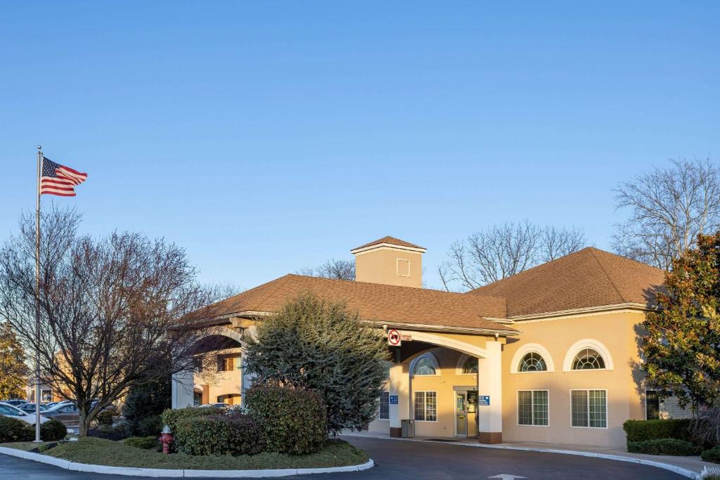 Um edifício com uma bandeira americana à frente. em Days Inn & Suites by Wyndham Cherry Hill - Philadelphia em Cherry Hill