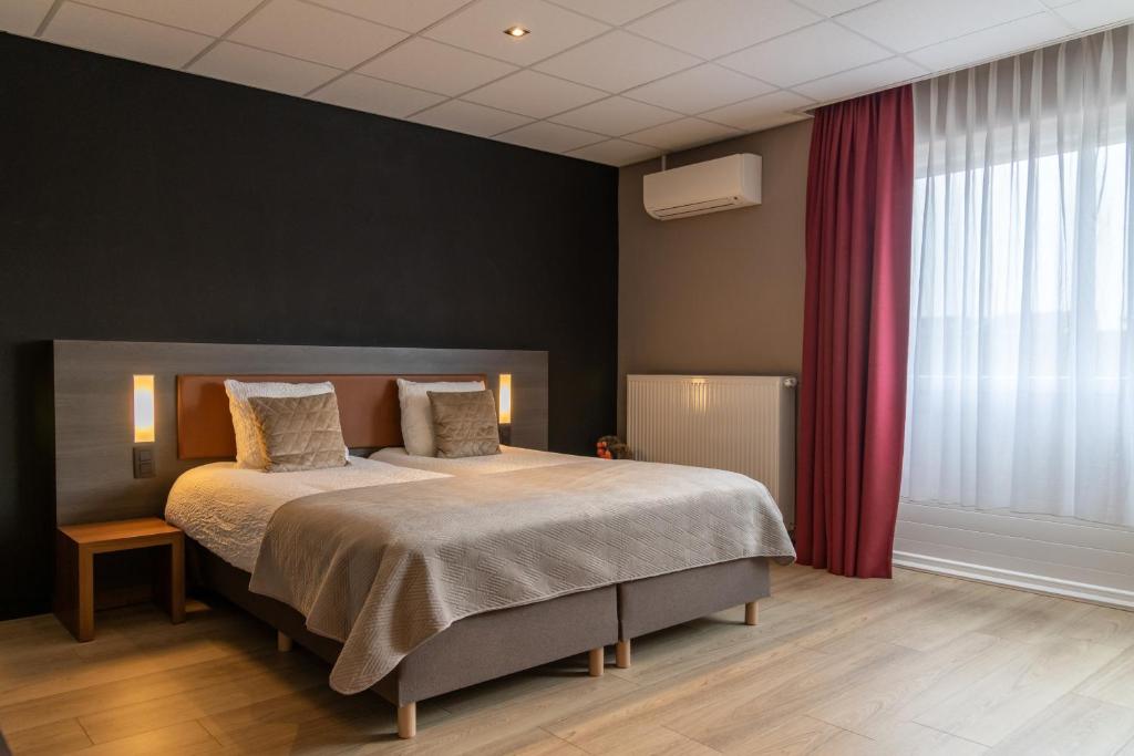 ein Schlafzimmer mit einem Bett und einem roten Vorhang in der Unterkunft Hotel Rooms in Breskens
