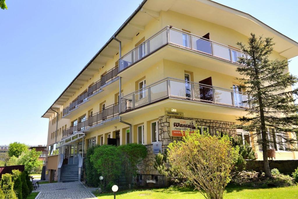 a large yellow building with a tree in front of it at Wanta in Zakopane