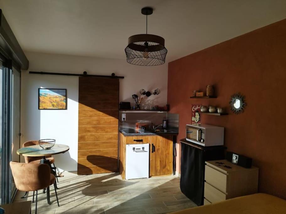 a kitchen with a small table and a white refrigerator at Le cocon Cévenol in Anduze