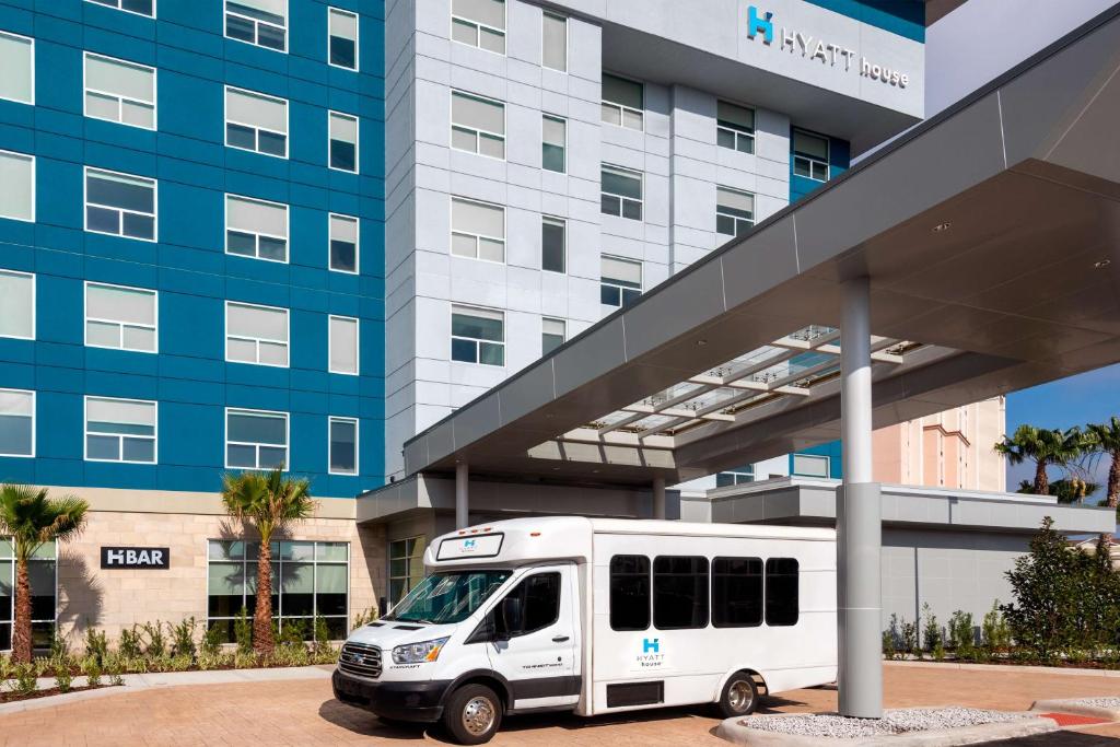 a white bus parked in front of a building at Hyatt House Orlando Airport in Orlando