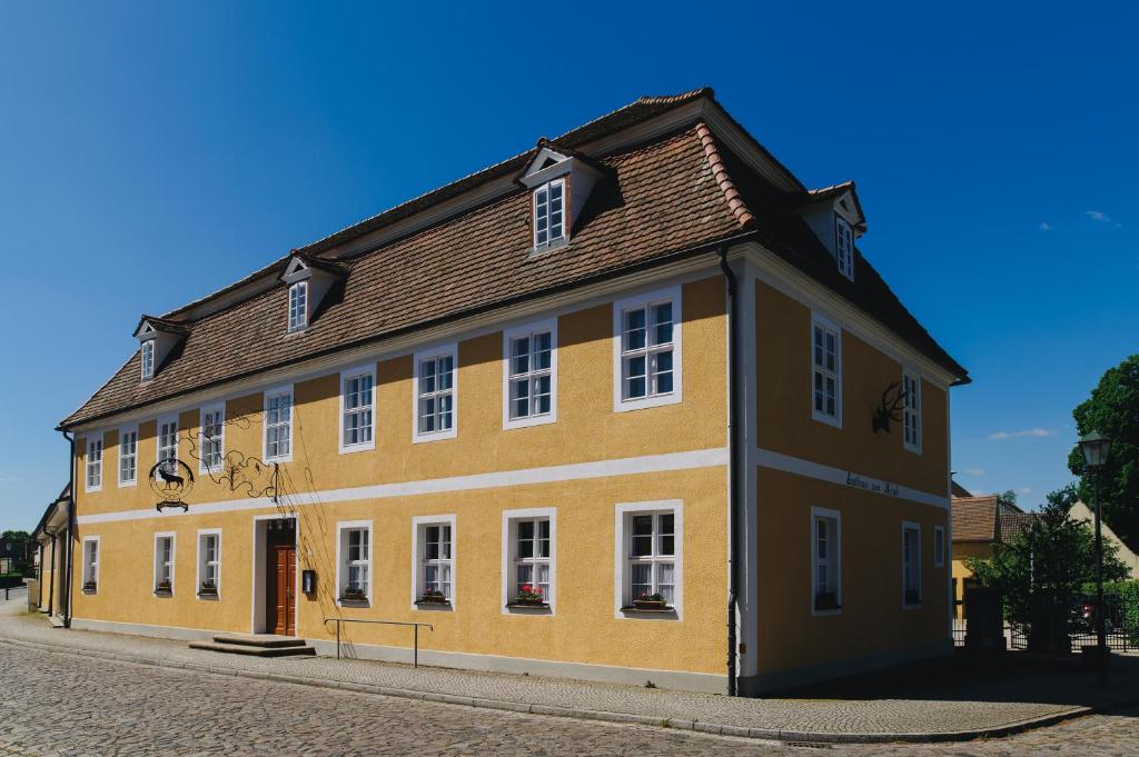 ein gelbes Gebäude mit braunem Dach auf einer Straße in der Unterkunft Gasthof Zum Hirsch in Drehna