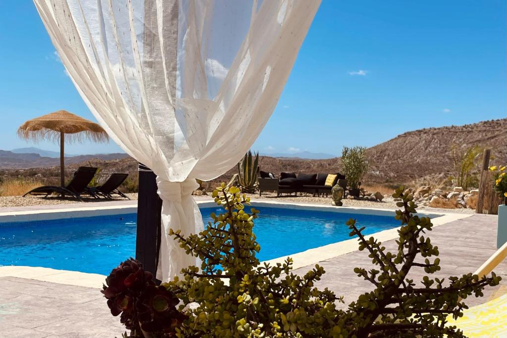 Una cortina blanca en un poste junto a una piscina en El sueño de Andalucia, en Huércal-Overa