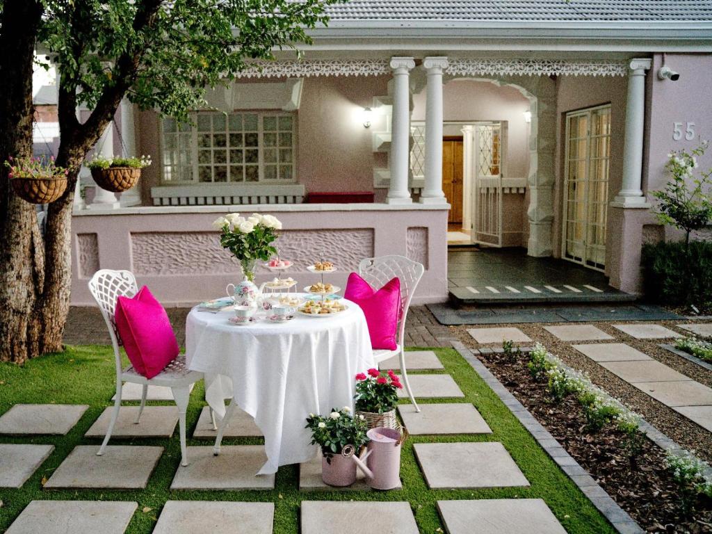 a table with pink chairs in a yard at The Sweet Rose in Bloemfontein
