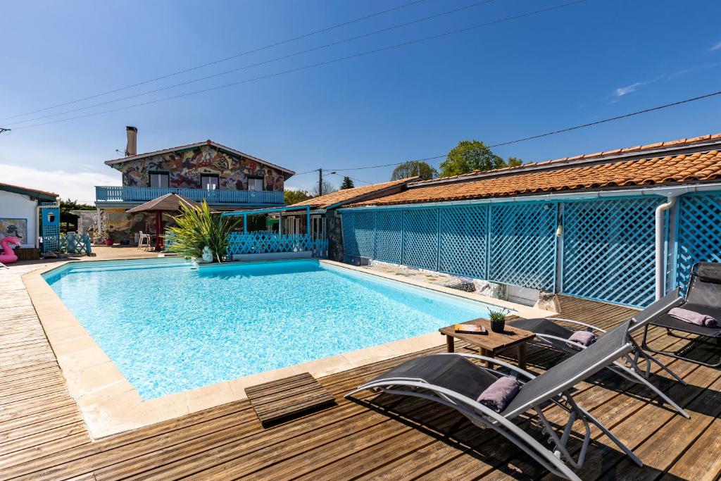 - une piscine sur une terrasse avec 2 chaises et une maison dans l'établissement Gîte 1 à la Maison Mosaïc, à Gaillan-en-Médoc
