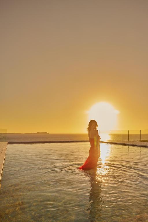 a woman standing in the water at sunset at The Signature Level at TRS Ibiza Hotel - All Inclusive Adults Only - Entrance to Clubs included in San Antonio