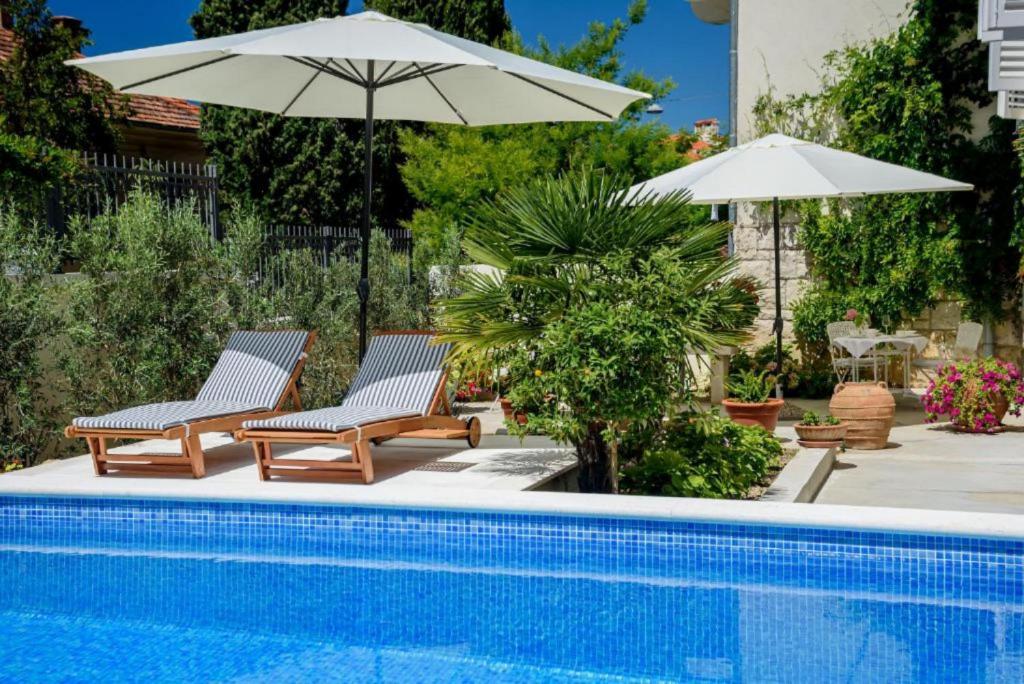 zwei Stühle und ein Sonnenschirm neben einem Pool in der Unterkunft Palace Schön Milesi - esense of prestige - BURALUX properties in Split