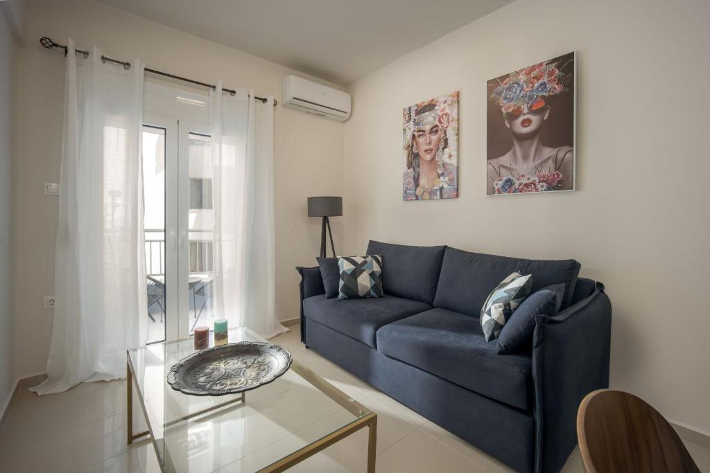 uma sala de estar com um sofá azul e uma mesa de vidro em Downtown Guesthouse by Estia em Heraclião