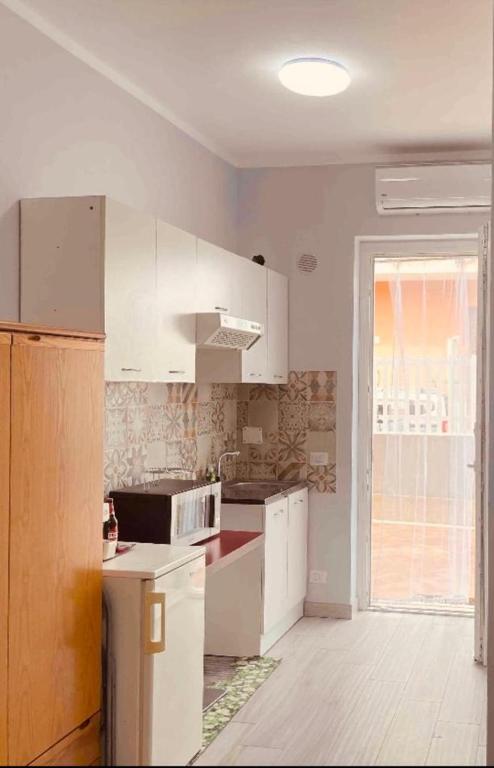 an empty kitchen with white cabinets and a window at M&C Apartment in Fiumicino