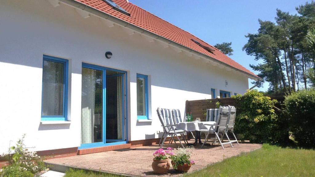 een wit huis met een tafel en stoelen op een patio bij Ferienhaus Schüler mit Terrasse und Garten in Zinnowitz