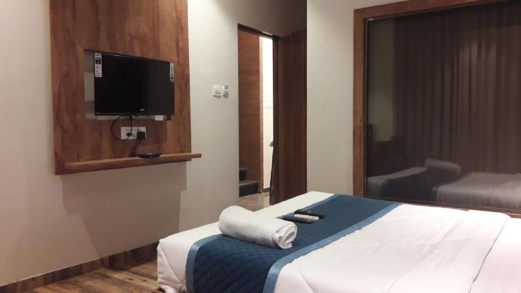 1 dormitorio con 1 cama y TV en la pared en Shine Hospitality Palace, en Bombay