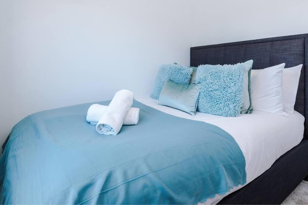 a large bed with blue and white pillows at Full SKY TV Access 2BR Stylish Apartment in Hough Green