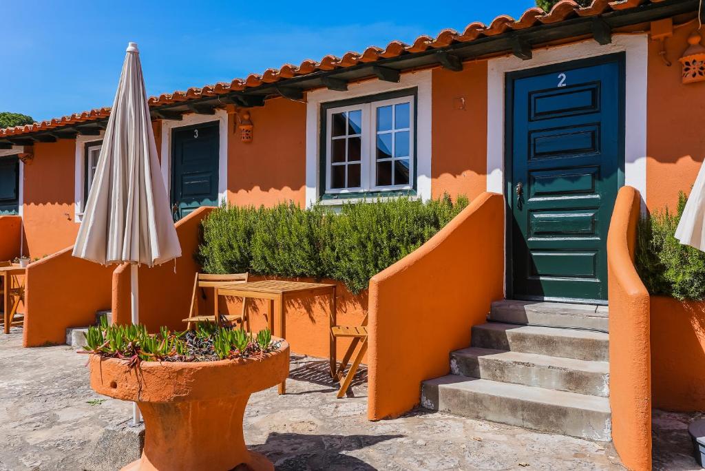 an orange house with a green door and an umbrella at Quinta da Bicuda in Cascais