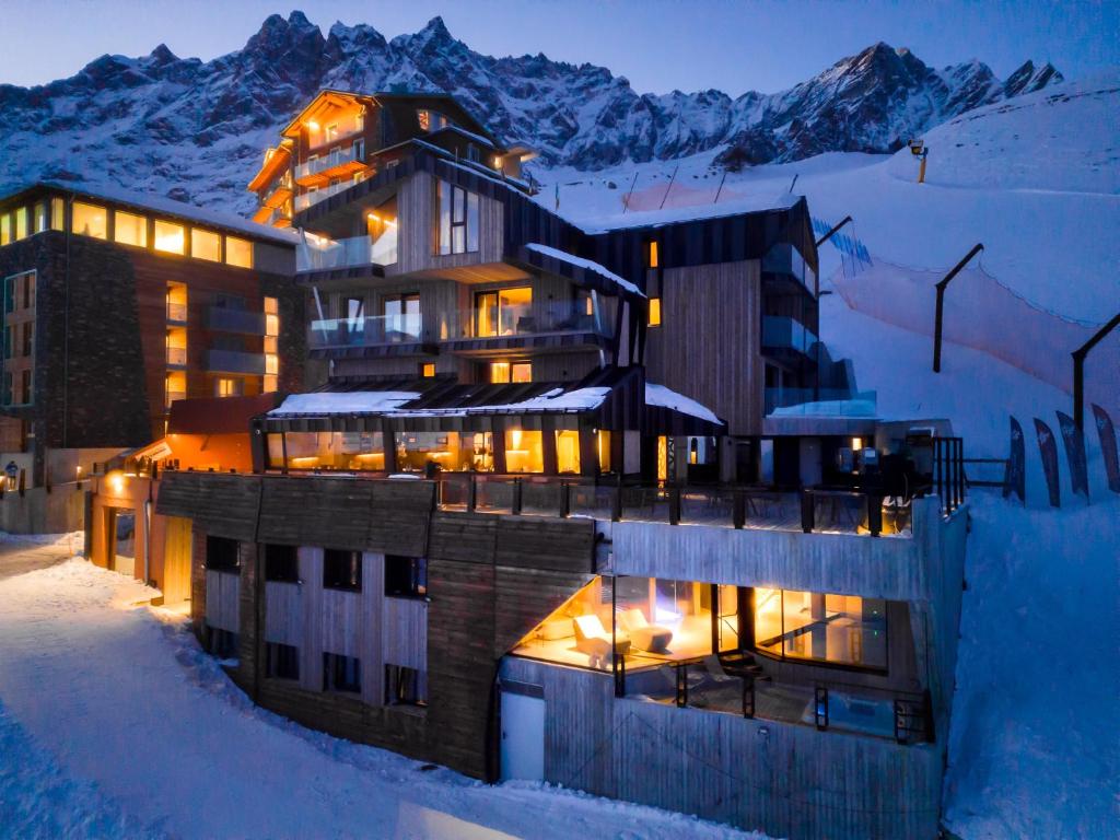 un bâtiment dans la neige la nuit avec de la neige dans l'établissement Bergman Mountain Hotel, à Breuil-Cervinia