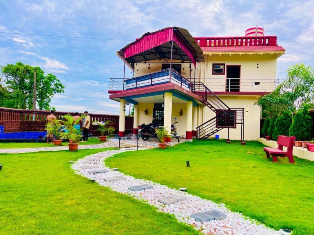 una casa con techo rojo y césped verde en Goroomgo Bottom Up Villa Swimming Pool Bhubaneswar en Bhubaneshwar