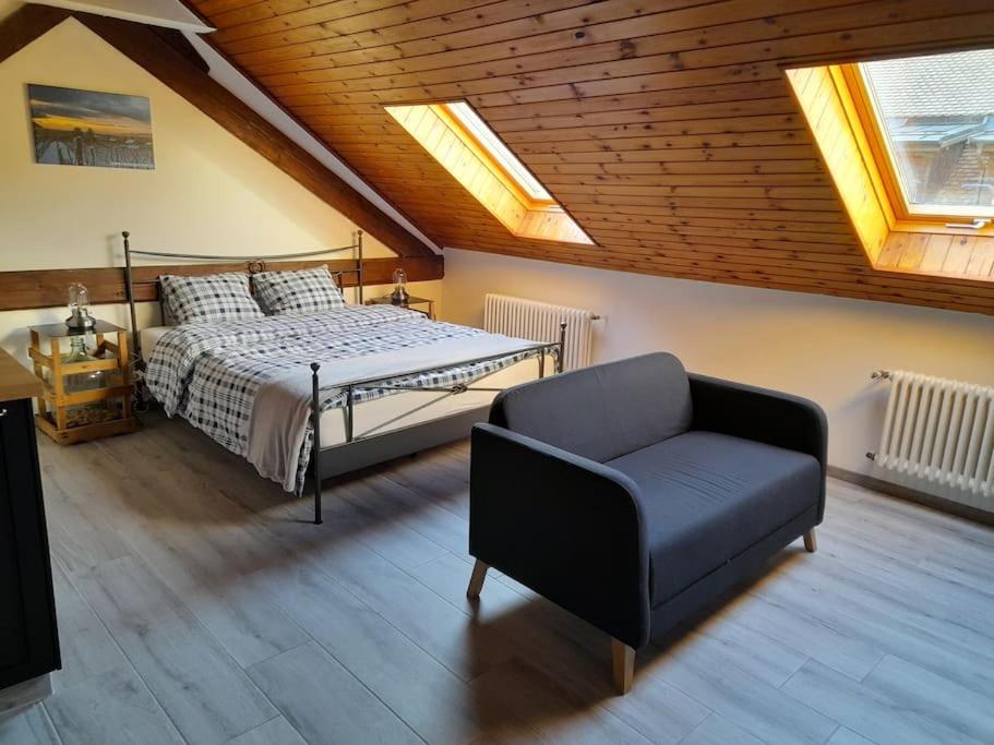 een slaapkamer met een bed, een stoel en dakramen bij Studio mansardé chez un vigneron au village in Villeneuve