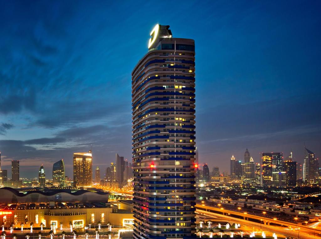 a tall building in a city at night at DAMAC Maison Mall Street in Dubai