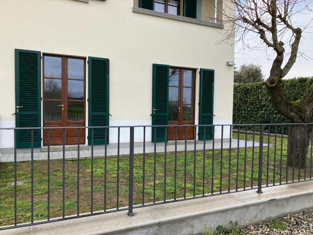 una recinzione di fronte a una casa con persiane verdi di Acero a Cortona
